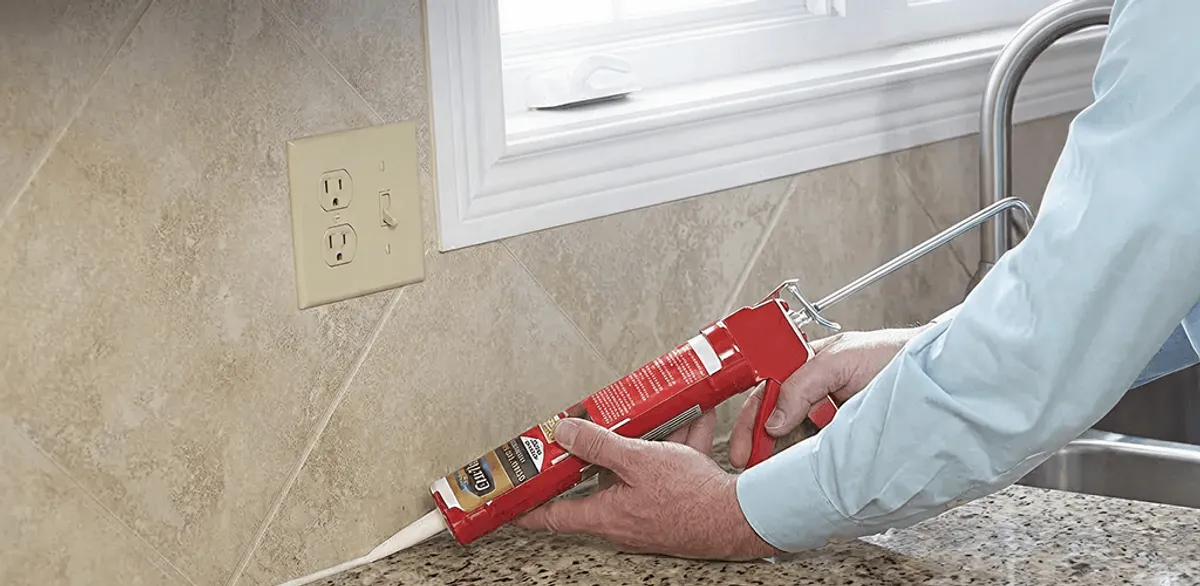 Handyman applying caulk along a kitchen backsplash and countertop seam in Albany, NY